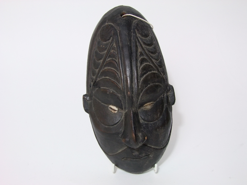 An old African hardwood facial mask with Cowrie shell eyes and geometric carving to the forehead