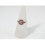 An 18ct gold diamond and ruby ring, the central diamond with a ring of eight rubies, size N