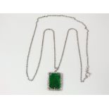 An 18ct white gold pendant supporting a carved jade panel, hung from a fine link chain