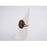 A 14ct gold pink stone and diamond set ring, the central stone surrounded by fourteen diamonds, size