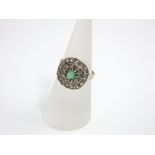 A white gold ring mounted with two tiers of diamonds (26) and central emerald, size M