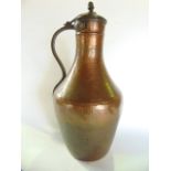 An eastern copper ewer with hammered finish, ironwork handle and hinged cover height 55cm