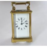 A brass carriage clock with eight day striking movement and enamelled dial