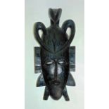 A carved African mask, on the head of which stands a crouching bird