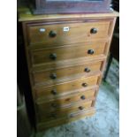 A pine upright bedroom chest fitted with six long shallow drawers with turned button knob handles