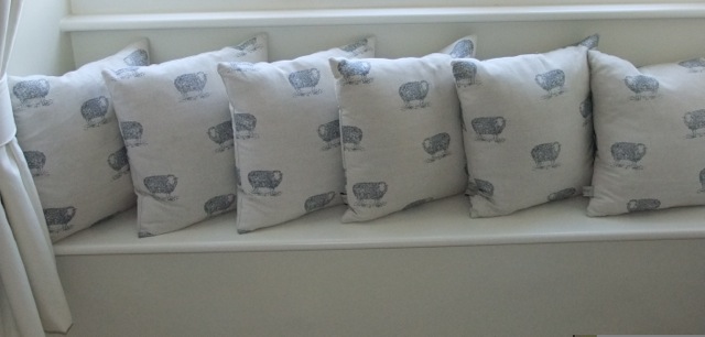 A collection of six linen cushions by Emily Bond with sheep detail