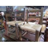 Two rustic fruitwood side chairs with rail backs, rush seats set on square cut supports and rails