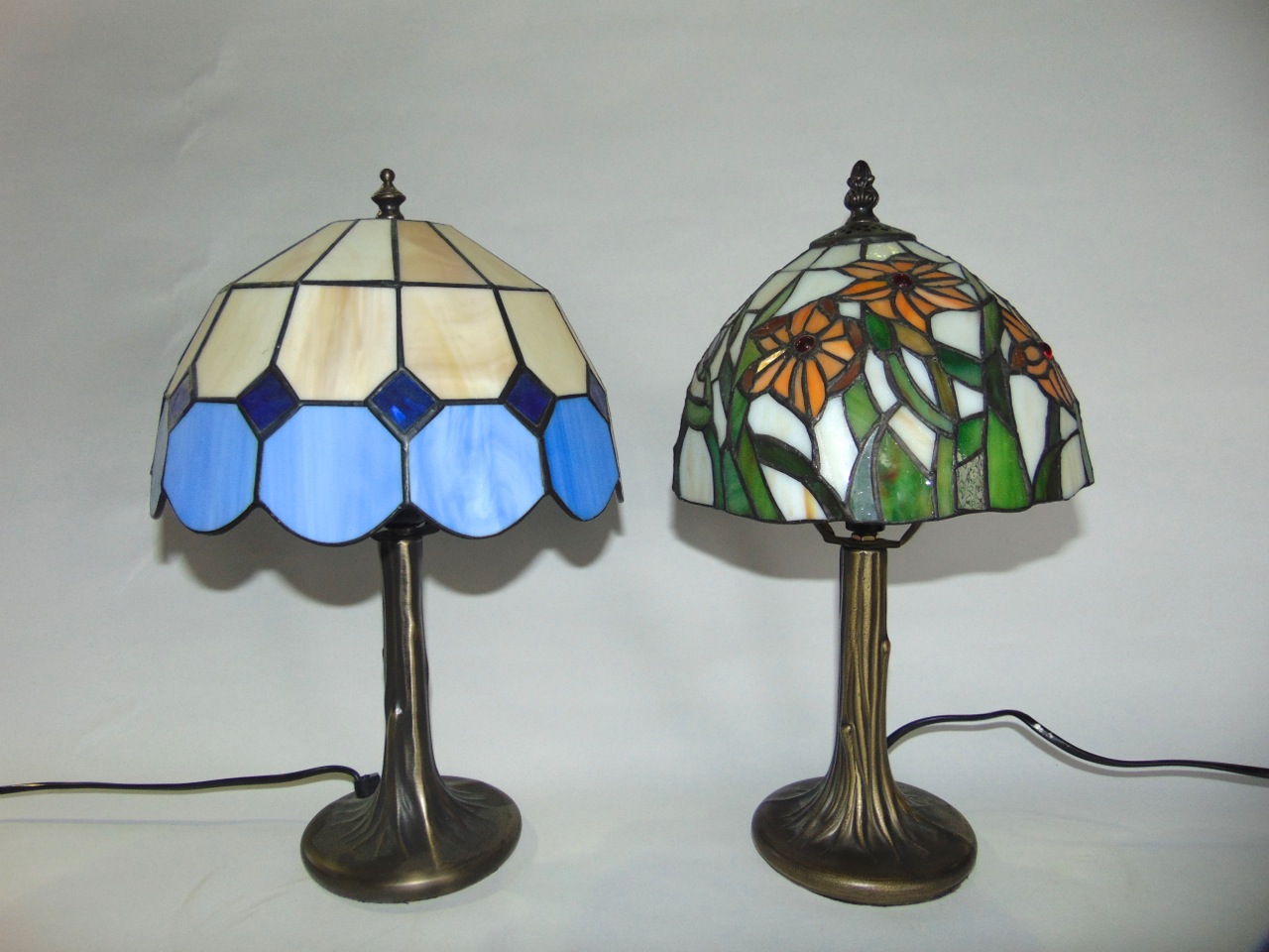 Two reproduction table lamps with leaded glass shades raised on simulated trunk like stems