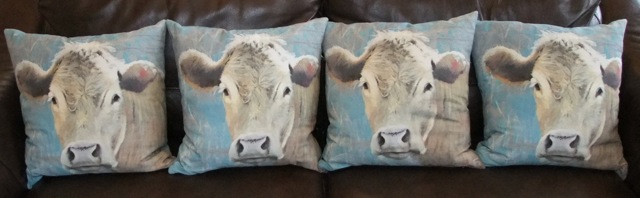 A set of four printed linen cushions, each showing a cows head