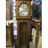 A reproduction long case clock with moulded case work and arched dial