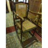 A vintage invalid chair, the stained beechwood frame with crook handles and cane seat and back