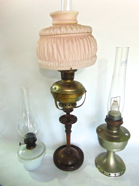 an Edwardian oil lamp raised on a turned walnut base and column, together with two further lamps