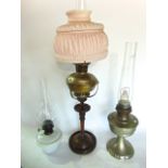 an Edwardian oil lamp raised on a turned walnut base and column, together with two further lamps