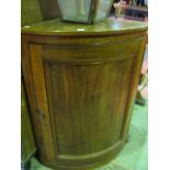 A 19th century mahogany bow fronted and freestanding corner cupboard of half height enclosed by a