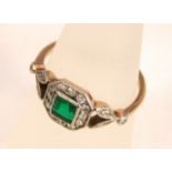 An Art Deco emerald and diamond plaque ring with central square cut emerald surrounded by single cut