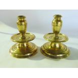 A pair of 18th century Dutch brass candlesticks raised on wide span bases, with drip pan and urn
