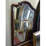 A wall mirror, the mahogany frame with stepped and moulded arched outline enclosing a bevelled