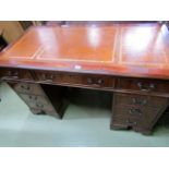 A reproduction Georgian style kneehole writing desk of nine drawers with inset brown leather top