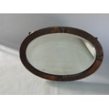 An arts and crafts style wall mirror of oval form, with bevelled edge plate and planished copper