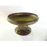An arts and crafts hammered tin ware table centre raised on three short supports and domed base