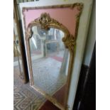 A wall mirror, the gilded and moulded frame with foliate detail mounted on a painted rectangular and