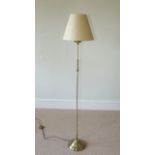 A contemporary standard lamp with brushed brass finish and pale cream conical shaped shade