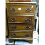 A small reproduction yew wood veneered four drawer bedside chest in the Georgian style raised on