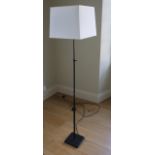 A contemporary lamp standard with adjustable column in a black colourway with square tapered cream