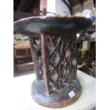 An African carved hardwood stool, the dished top raised on a pair of geometric pierced supports