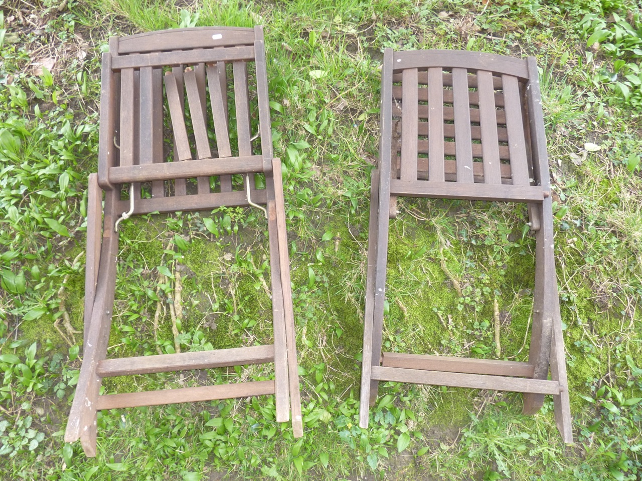 A pair of contemporary stained hardwood folding garden chairs with slatted seats and backs