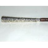 A walking cane with six inch African white metal handle decorated with jungle scenes