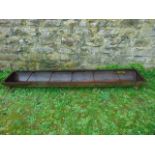 A vintage cast iron pig feeding trough of rectangular form with 5 rung divisions, 6ft long approx