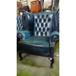 A pair of chesterfield style button and wing back lounge chairs in blue with studded decoration with