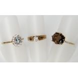 Three 9ct gold rings to include a smokey quartz ring in an eight prong setting with diamond chip