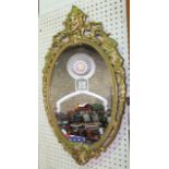 A gilt cast metal framed oval wall mirror in the neo classical manner mounted with a female face