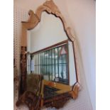 A Venetian glass wall mirror with arched outline set within a peach coloured glass frame with etched