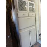 A 1950s kitchenette fitted with twin glazed doors over two cupboard doors, the fall front