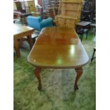 An Edwardian mahogany extending dining table of Queen Anne style with gadrooned border, two