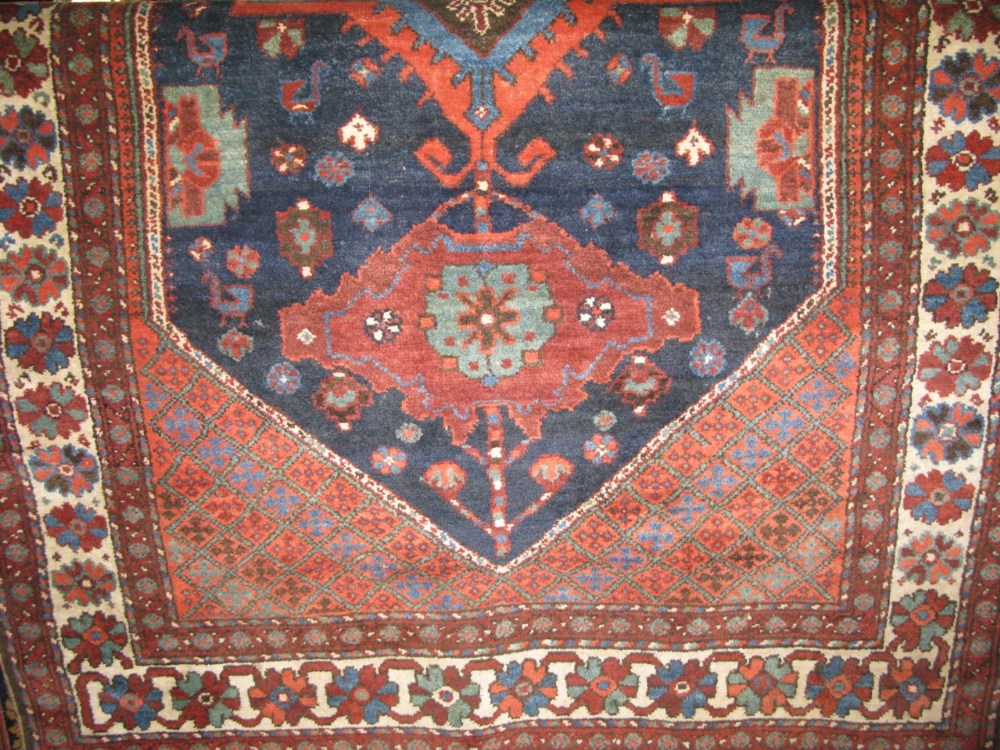 A Persian wool floor rug centrally decorated with large medallions and diaper panels upon a rich