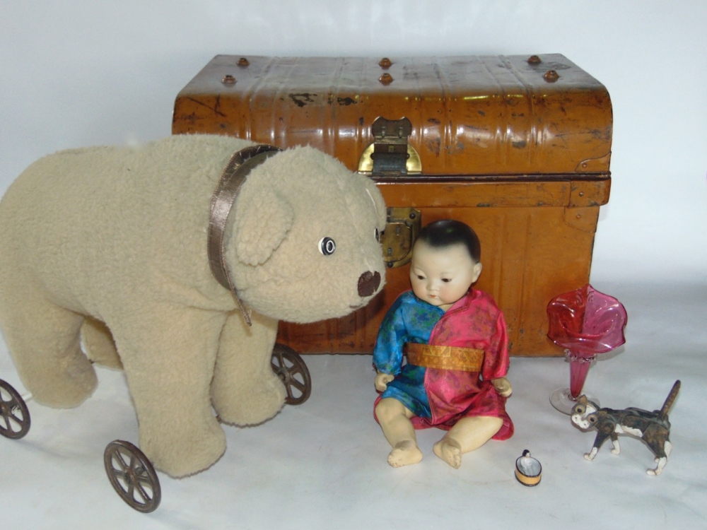 A tin trunk containing a collection of various vintage toys to include a polar bear on a trolley and