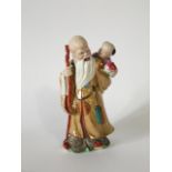 An oriental figure group of an elderly bearded man and a child on his back carrying a staff with