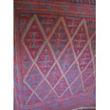 A tribal Kazak rug decorated with red and blue diamonds upon a blue ground, 101cm x 117cm