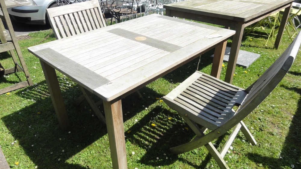 A Barlow Tyrie teak wood garden table with slatted top and two matching folding chairs