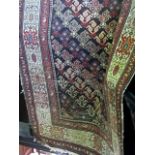 A Persian type floor rug geometrically decorated with red, black and yellow diagonal medallions upon