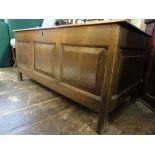 An 18th century oak coffer with plank top, the front elevation enclosing three rectangular fielded