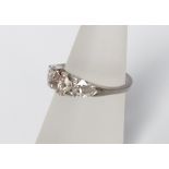 A platinum three stone diamond ring centrally set with round brilliant cut cognac coloured diamond