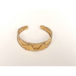 An 18ct cast gold bangle of heavy gauge with modernist scrolling design