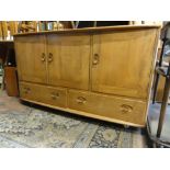 An Ercol light elm sideboard fitted with three cupboard doors over two drawers upon castors, 76 cm