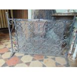 A hand wrought iron fire screen with fleur de lys and scroll detail, 75cm wide