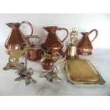 A graduated set of three copper jugs together with a further copper kettle and a cast brass hand